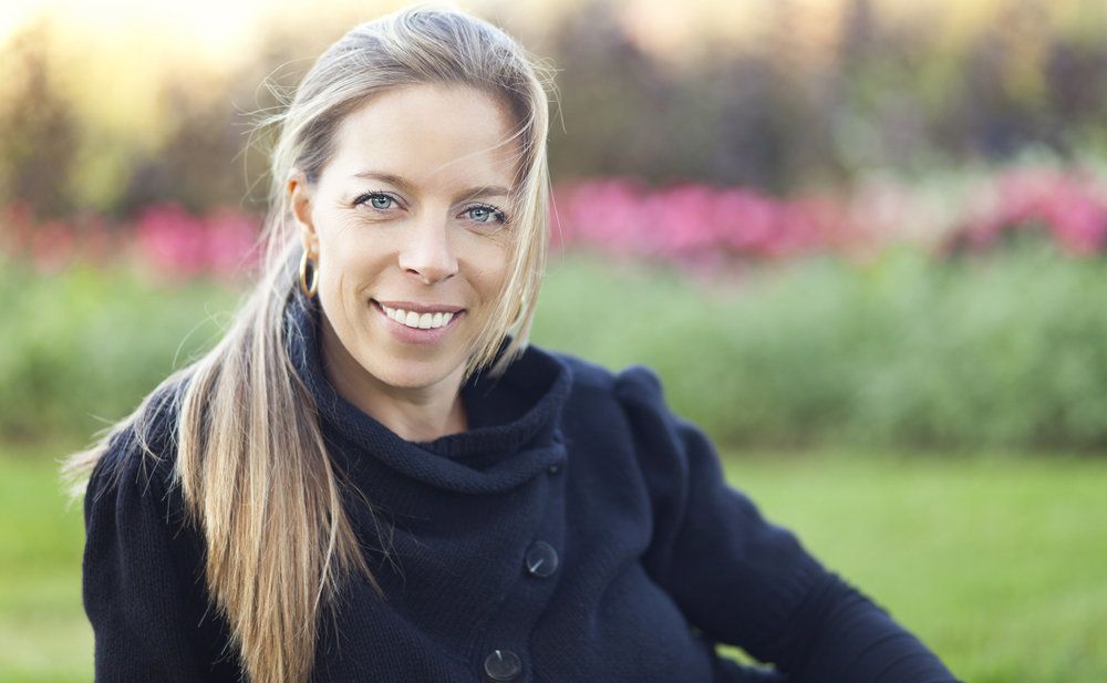 Femme souriante, assise à l’extérieur